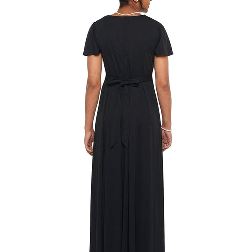 Back view of the Jenna High Scoop Neck flutter sleeve dress in black, showcasing the full-length flowing skirt, softly draped fabric, and tied waist detail, designed for choir, show choir, and formal performance wear.