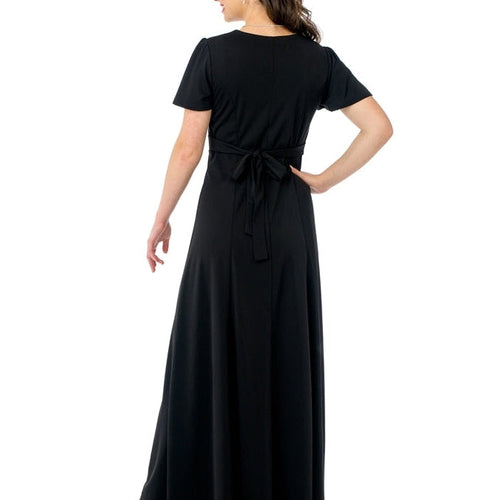 Back view of the Joanna sweetheart neck flutter sleeve dress in black, showcasing a flowing floor-length skirt and adjustable waist tie, designed for formal occasions, choir performances, and elegant stage wear.