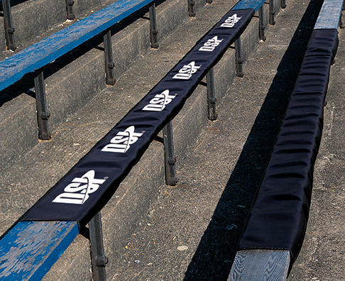 DSI padded bleacher cover installed on stadium seating, featuring durable black protective padding designed to improve spectator comfort and safety on metal and wooden bleachers.