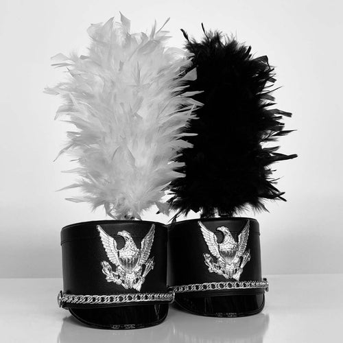 DSI French upright marching band plumes in black and white, mounted on black shakos with silver eagle insignia and decorative chain trim, designed for drum corps and marching band uniforms.